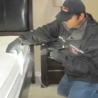 Bed bug inspection technician checking a mattress and bed frame for signs of infestation in Indianapolis, IN
