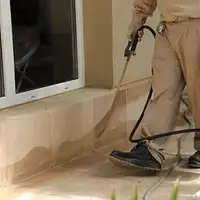General pest control technician spraying exterior perimeter around a home in Indianapolis, IN