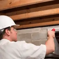 Termite inspection technician checking a basement wall and framing for termite activity in Indianapolis, IN